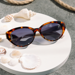 Peepers En Route Sunglasses in Tortoise/White on a white table with seashells