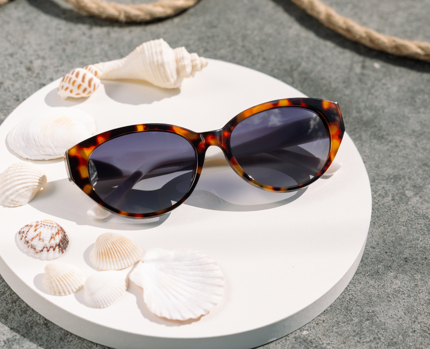 Peepers En Route Sunglasses in Tortoise/White on a white table with seashells
