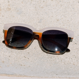 Peepers Frenchy Sunglasses in Mocha Tortoise/Cream resting on a stone surface