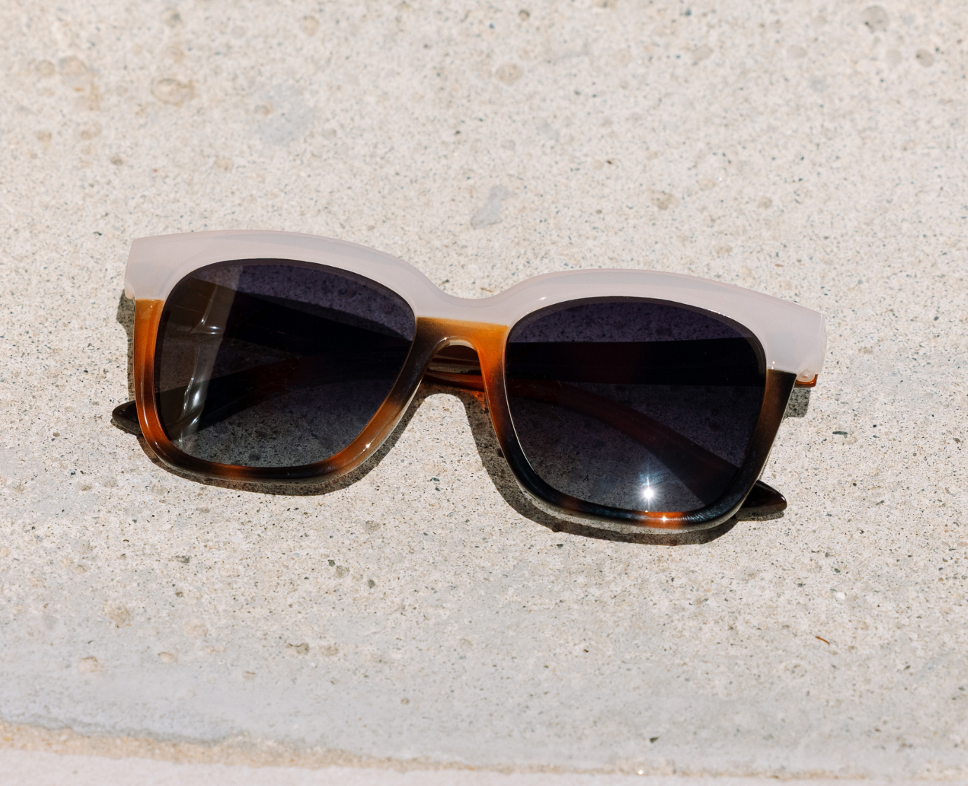 Peepers Frenchy Sunglasses in Mocha Tortoise/Cream resting on a stone surface