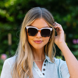 Smiling woman in a light blue top wearing Peepers Frenchy Sunglasses in Mocha Tortoise/Cream