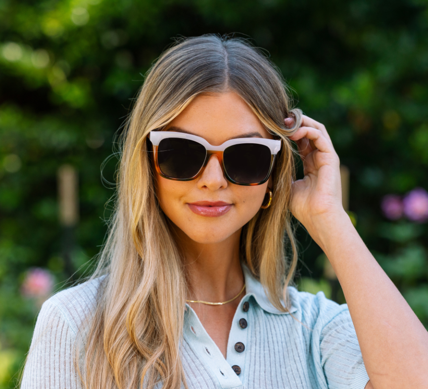 Smiling woman in a light blue top wearing Peepers Frenchy Sunglasses in Mocha Tortoise/Cream
