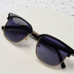 Peepers Houston Sunglasses in Black resting on a white surface