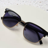 Peepers Houston Sunglasses in Black resting on a white surface
