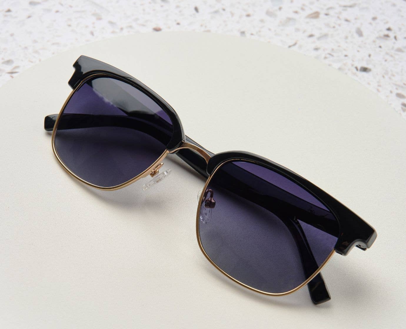 Peepers Houston Sunglasses in Black resting on a white surface
