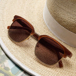 Peepers Houston Sunglasses in Brown resting on a straw hat