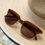Peepers Houston Sunglasses in Brown resting on a straw hat