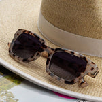 Peepers Myrtle Sunglasses in Gray Tortoise resting on a straw hat