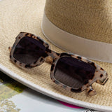 Peepers Myrtle Sunglasses in Gray Tortoise resting on a straw hat