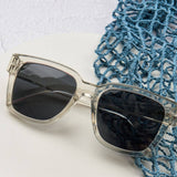 Peepers Paloma Sunglasses in Fog resting beside a blue net bag
