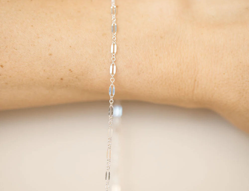 A sterling silver permanent bracelet welded closed on a wrist, no clasp, fitted in store at Desert Sol in Moab.