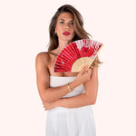 Woman in a white dress holding the Powder Designs Satin Fan in Rouge Blooms