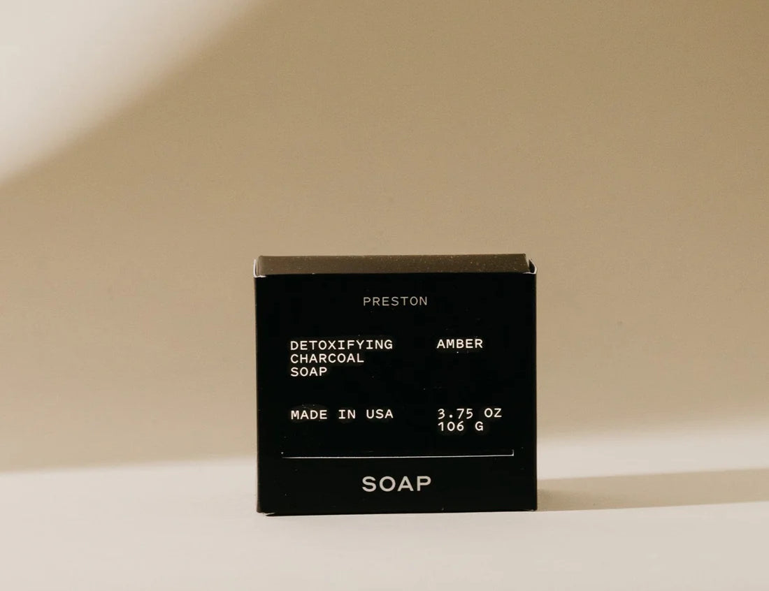 Preston Bar Soap in Amber, black boxed detoxifying charcoal soap on a tan background
