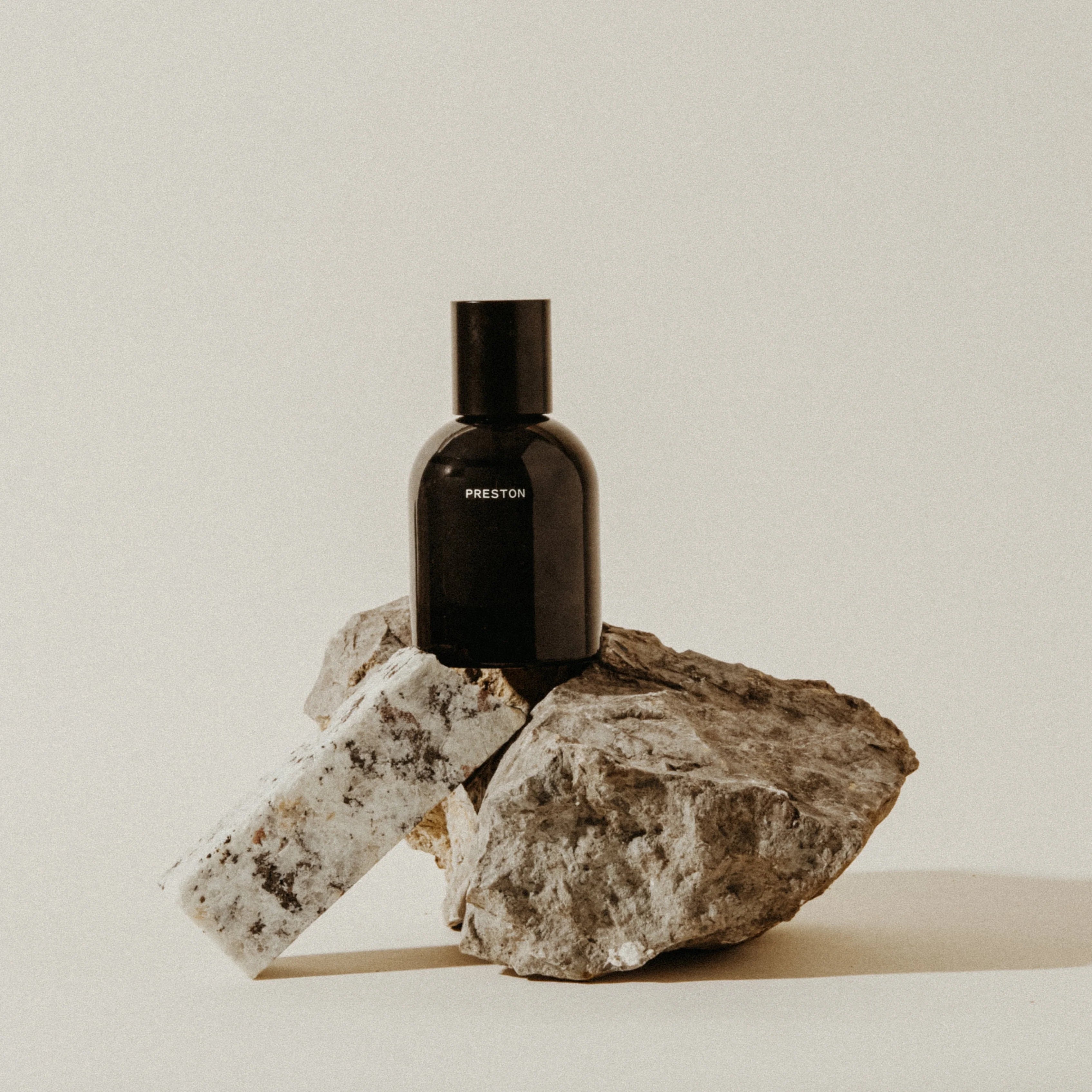 Preston Cologne matte black bottle resting on a rough stone