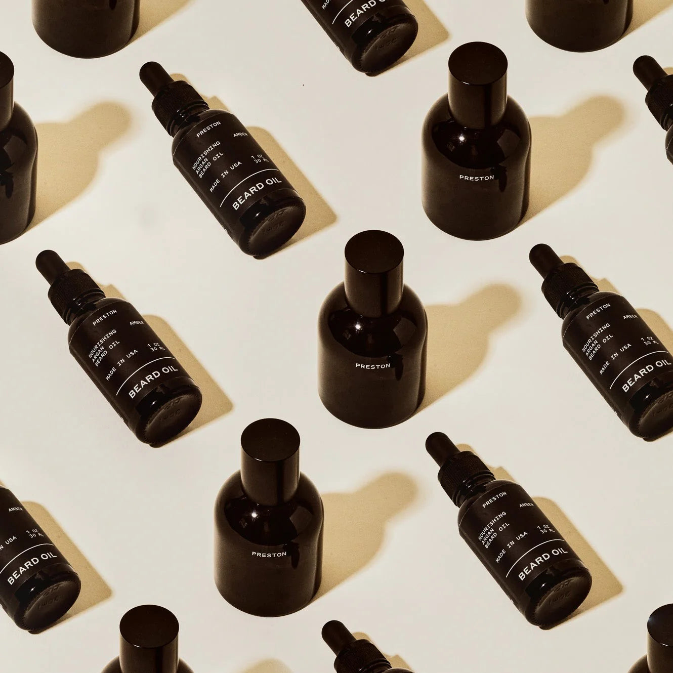 Rows of Preston Cologne matte black bottles arranged on a cream surface, from above