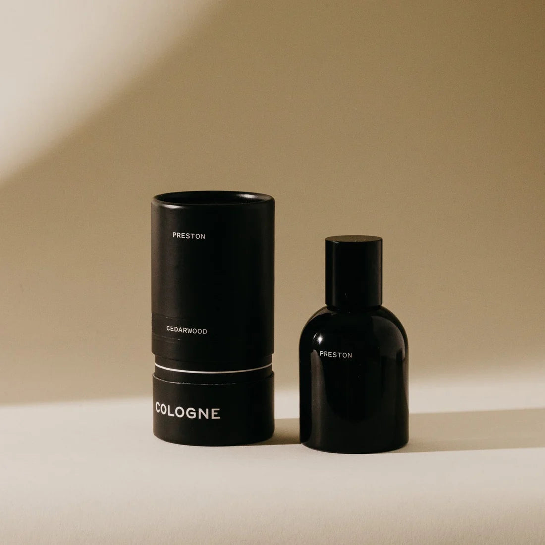 Preston Cologne in Cedarwood, a matte black bottle beside its black cylinder box