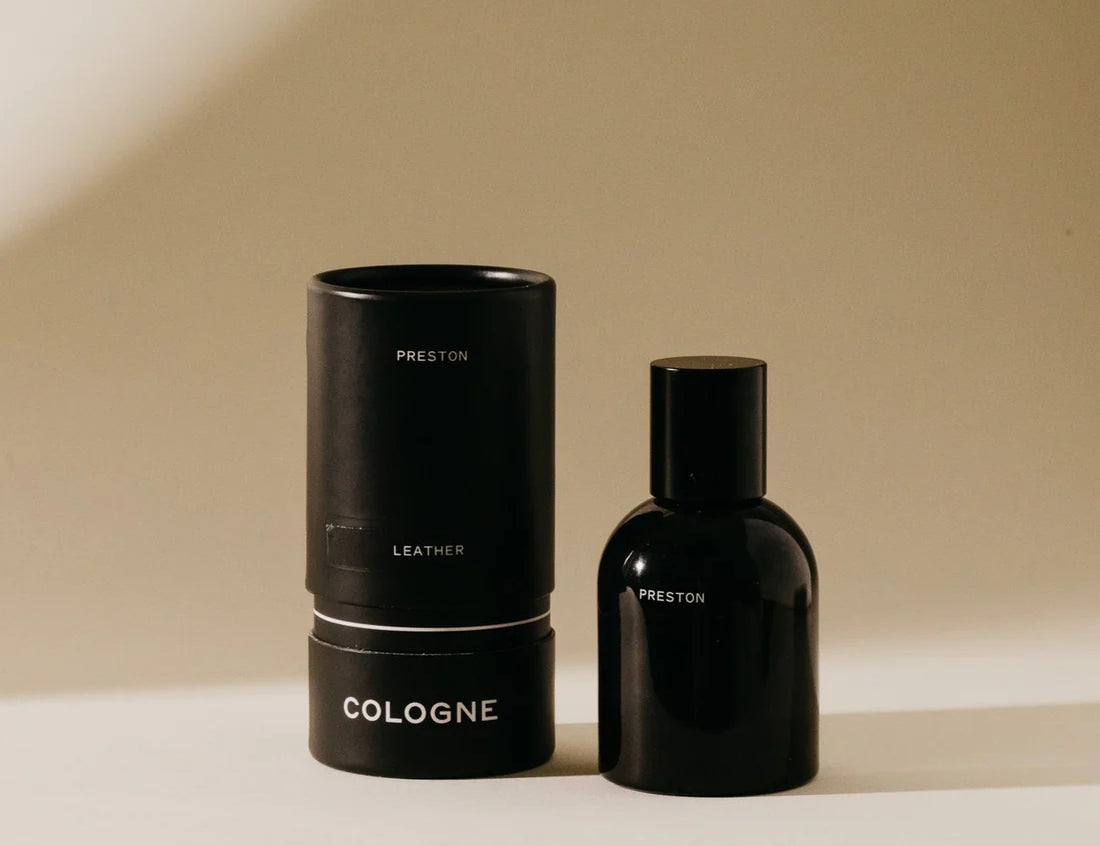 Preston Cologne in Leather, a matte black bottle beside its black cylinder box