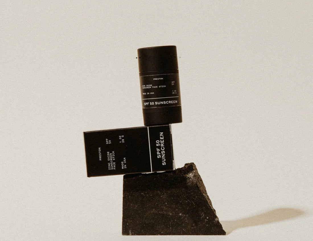 Preston Sunscreen Stick SPF 50 and its box balanced on a dark stone