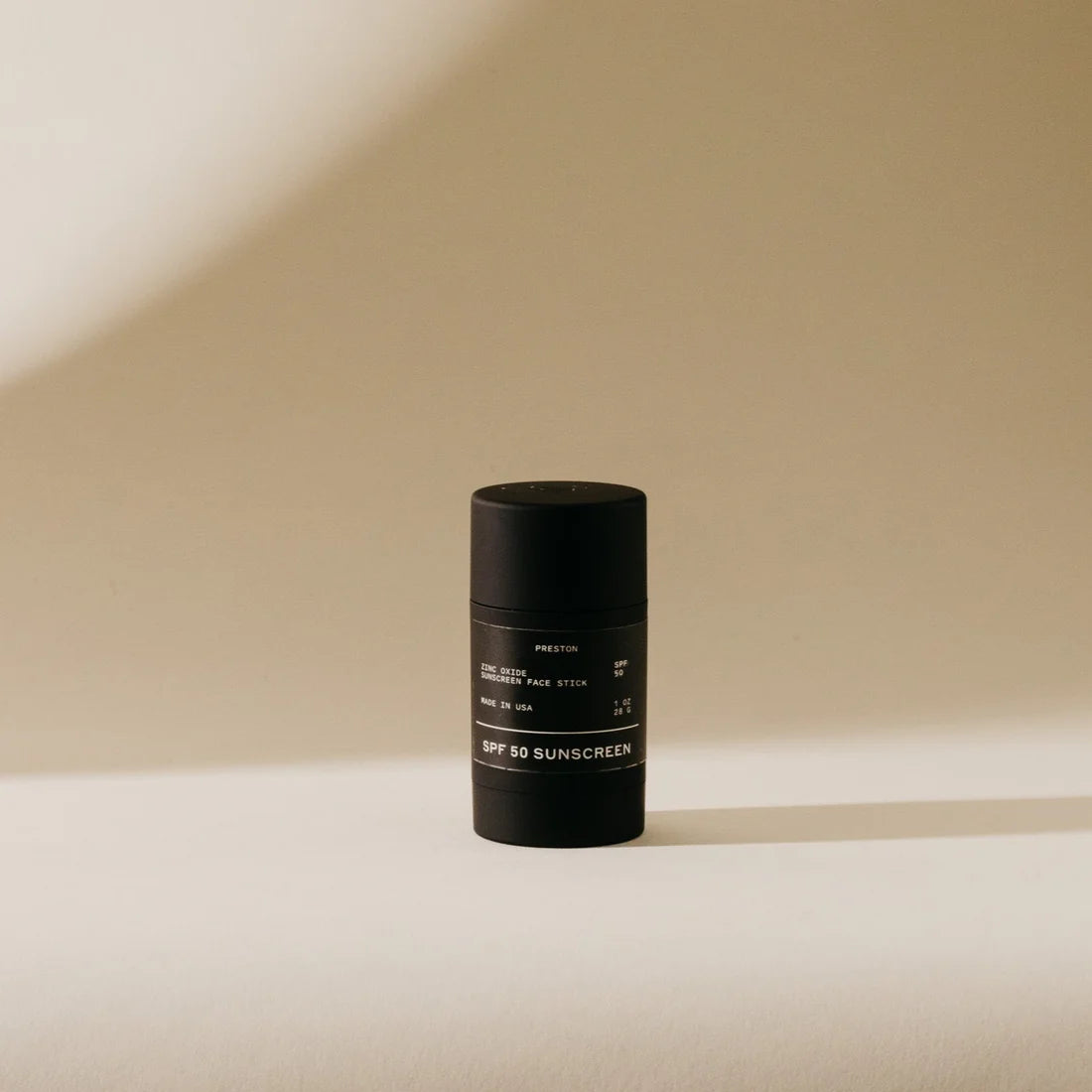 Preston Sunscreen Stick SPF 50, a matte black stick standing in warm light