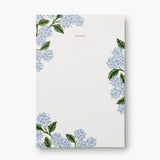 Rifle Paper Co. Hydrangea Memo Notepad, a cream pad with blue hydrangea illustrations in the corners