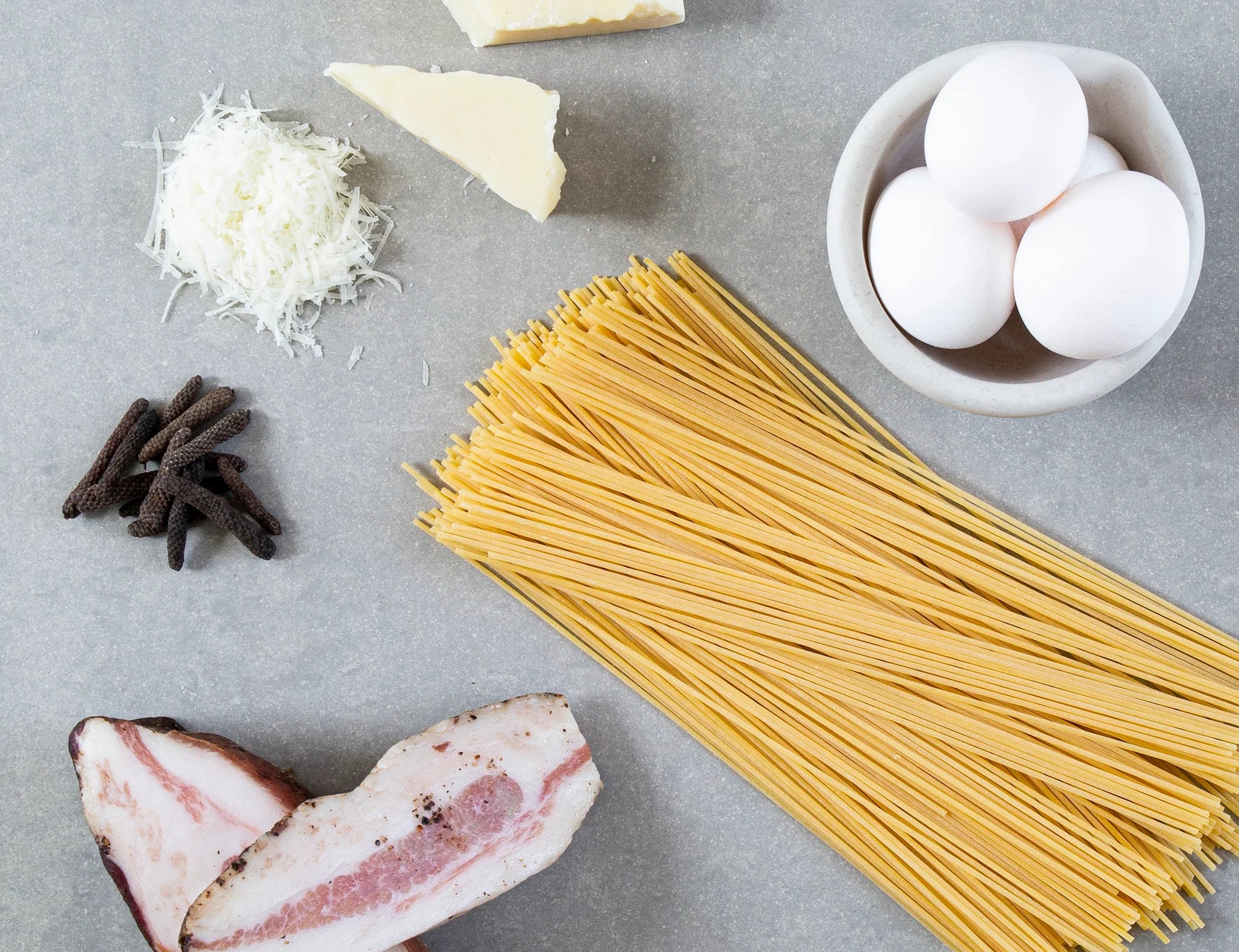 Rivsalt Java Long Pepper beside pasta, parmesan, eggs and pancetta ingredients