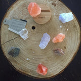Assorted Rivsalt salt rocks with a small grater on a round wood slab