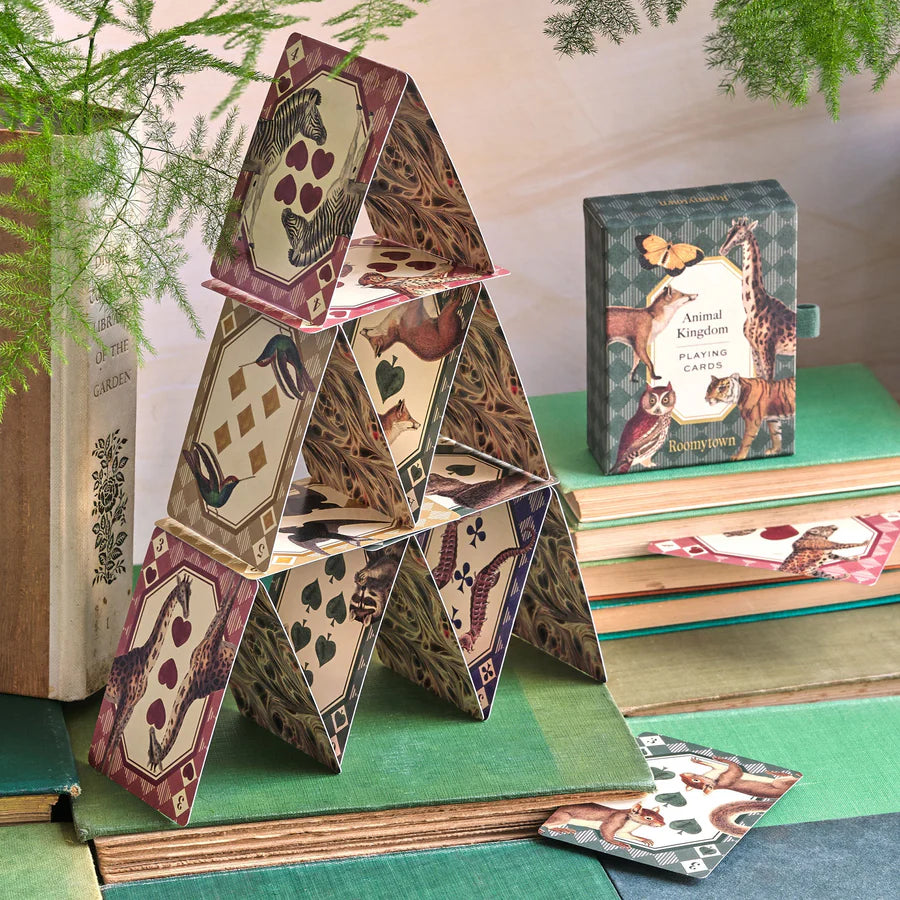 RoomyTown Animal Kingdom Playing Cards built into a house of cards on a green table beside the box