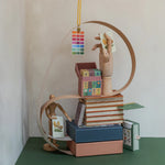 RoomyTown Festival of Flowers Playing Cards box styled on a stack of books with a wooden figure