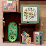RoomyTown Flower Clock 500-Piece Round Jigsaw Puzzle displayed on a shelf with matching botanical stationery