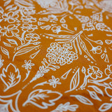 Close-up of the white wildflower print on the rust Rooted & Wild Adventure Co. Burn and Bloom Bandana