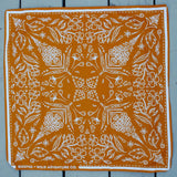 Rooted & Wild Adventure Co. Burn and Bloom Bandana, a rust orange bandana with a white wildflower print, laid flat