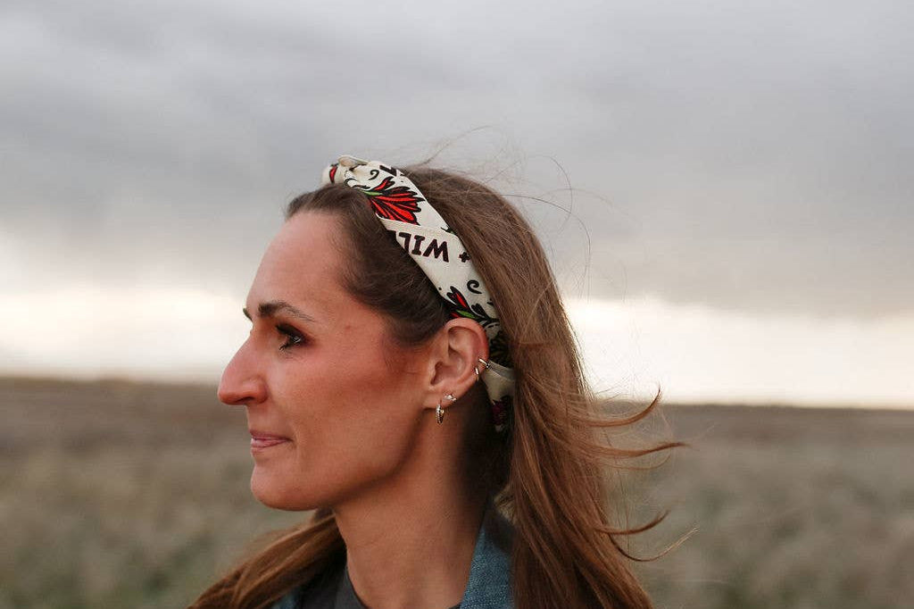 Woman in a denim jacket wearing the Rooted & Wild Adventure Co. Desert Bloom Bandana as a headband in a field