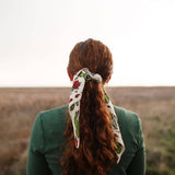 Back view of a woman with long red hair wearing the Rooted & Wild Adventure Co. Desert Bloom Bandana in her ponytail