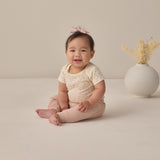 Rylee & Cru Baby Pant in Blush worn by a smiling seated baby in a cream top