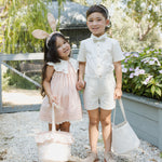 Girl in pink and boy in white wearing Rylee & Cru Bunny Headbands, smiling with Easter baskets