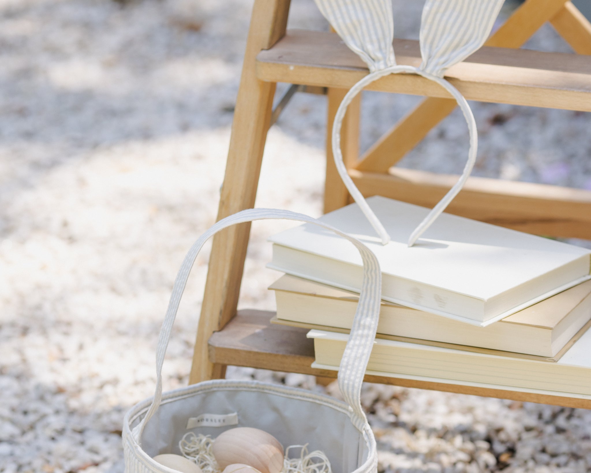 Rylee & Cru Bunny Headband in Sky Stripe resting on a stack of books beside an Easter basket
