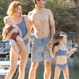 Family on a lake dock, baby wearing the Rylee & Cru Chocolate Moxie One-Piece with matching blue swimwear
