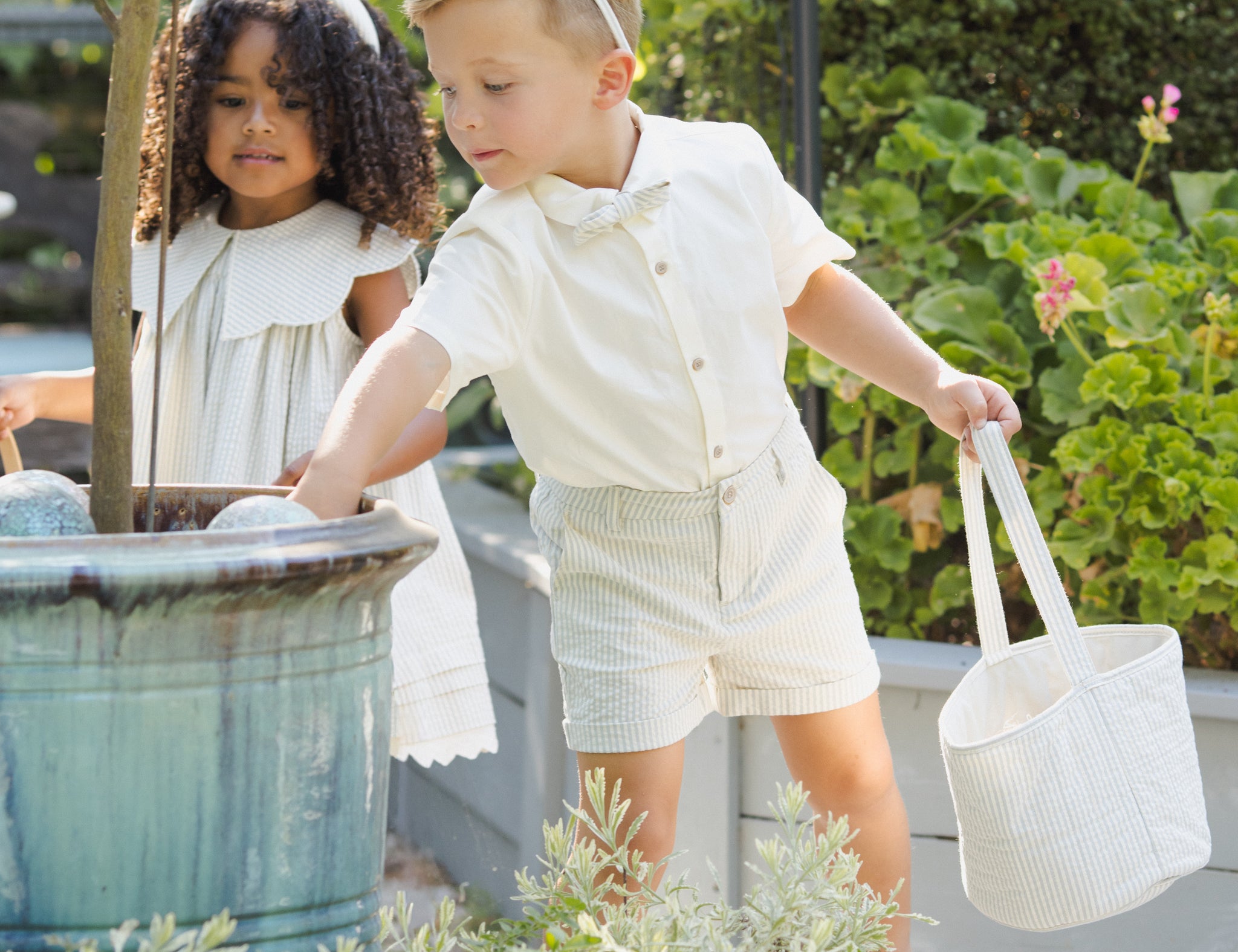 Two children in a garden with Rylee & Cru Easter Baskets in Sky Stripe and Eucalyptus Check