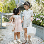 Girl in pink and boy in white carrying Rylee & Cru Easter Baskets along a gravel garden path