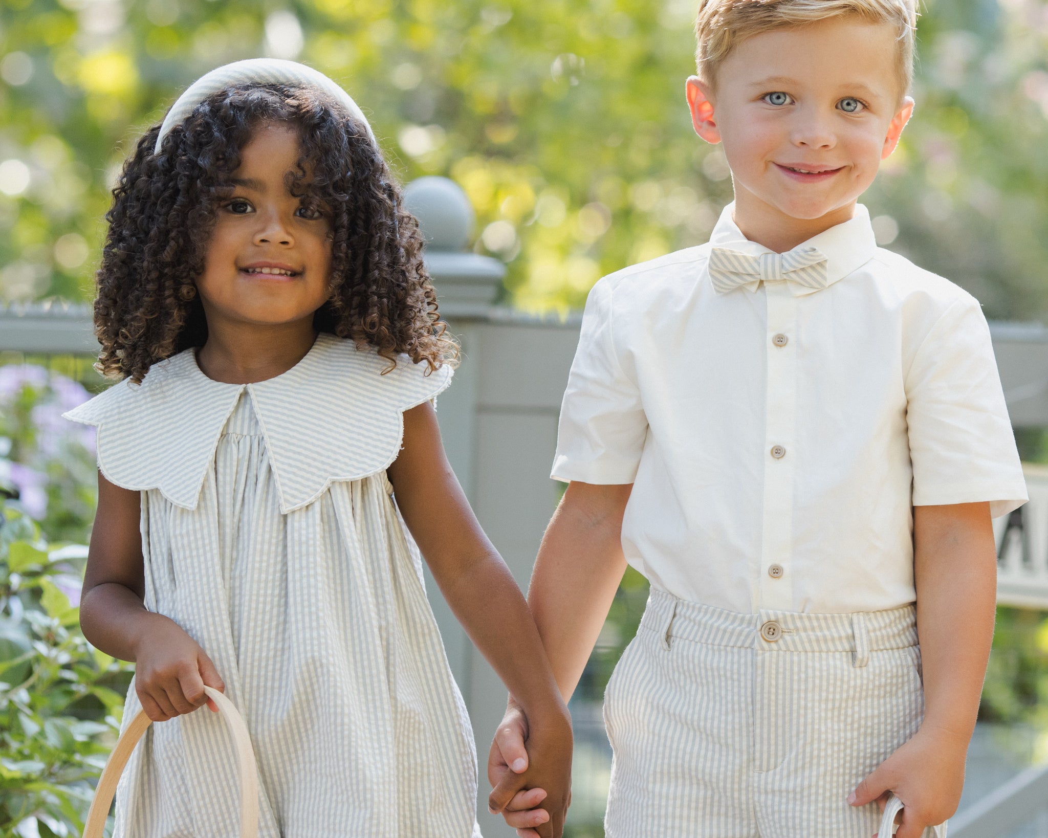 Girl and boy holding hands with Rylee & Cru Easter Baskets in a garden, close view
