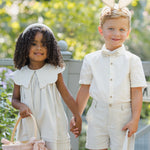 Girl and boy in cream Easter outfits holding hands and carrying Rylee & Cru Easter Baskets