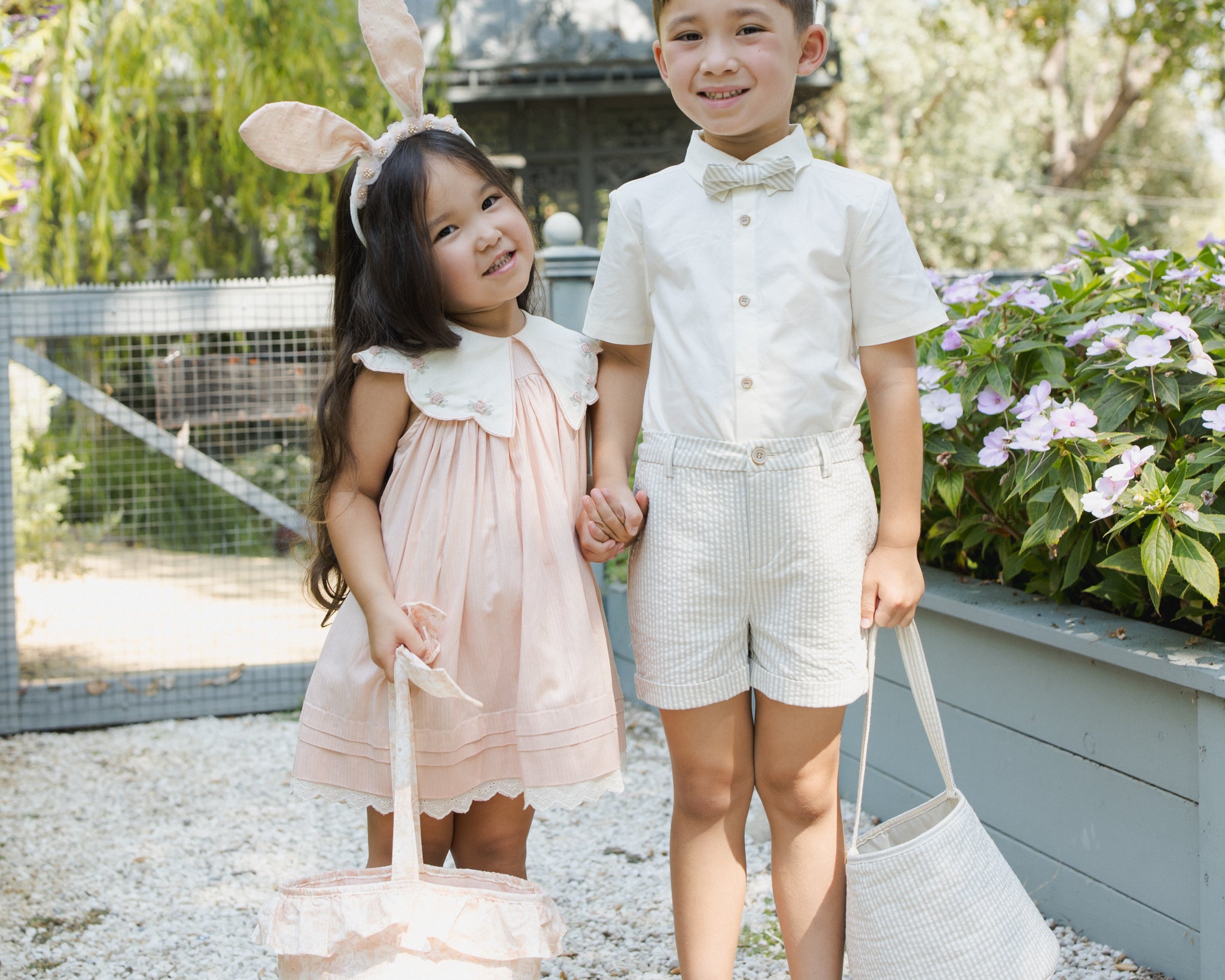 Girl in a pink dress and boy in a bow tie smiling with their Rylee & Cru Easter Baskets