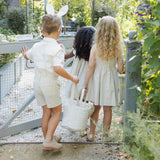 Three children with Rylee & Cru Easter Baskets walking away through a garden gate