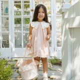 Girl in a pink dress with the Rylee & Cru Easter Basket in Pastel Garden standing at a greenhouse door