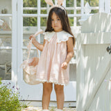 Girl in a pink dress and bunny ears holding the Rylee & Cru Easter Basket in Pastel Garden by a white gate