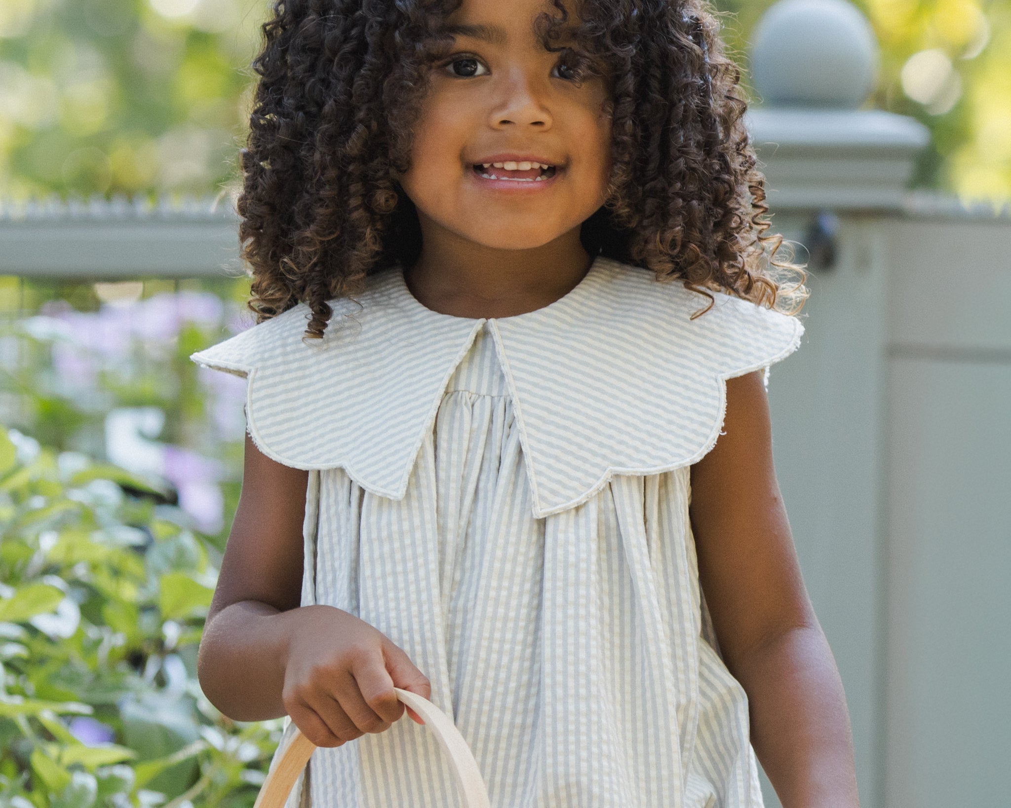 Smiling girl with curly hair holding a Rylee & Cru Easter Basket in Sky Stripe