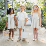 Three children in Easter outfits and bunny ears each holding a Rylee & Cru Easter Basket