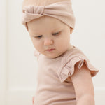 Close-up of a baby in a pink headband wearing the Rylee & Cru Flutter Sleeve Bodysuit in Blush