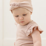Close-up of a baby in a pink headband wearing the Rylee & Cru Flutter Sleeve Bodysuit in Blush