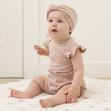 Baby in a pink turban headband sitting in the Rylee & Cru Flutter Sleeve Bodysuit in Blush with matching bloomers